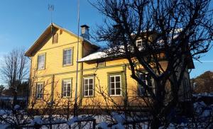 Una casa amarilla con un árbol delante. en Villa Jääskelä Hanko - koko talo en Hanko
