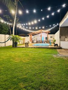 un patio trasero con piscina por la noche con luces en Bangalô Dunas, en Barreirinhas