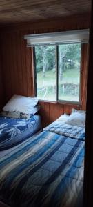 2 camas en una habitación con ventana en Hostal Carhuello, en Pucón
