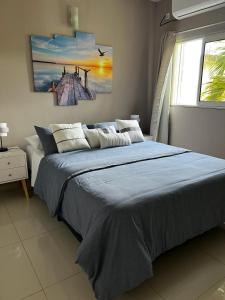 1 dormitorio con 1 cama con manta azul y ventana en The little Heaven, en Baie Nettle