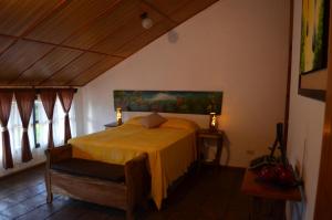 1 dormitorio con 1 cama con manta amarilla en Hostal Santa Clara B&B, en Apaneca