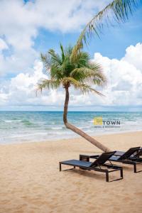 two lounge chairs and a palm tree on the beach at Luxy Park Hotel & Apartments - MTown in Phu Quoc