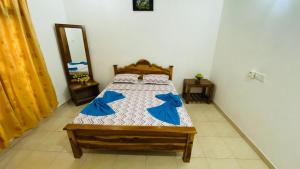 Schlafzimmer mit einem Bett mit blauer Bettwäsche und einem Spiegel in der Unterkunft Elephant safari Lodge sigiriya junction in Habarana
