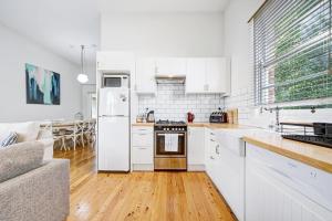 a kitchen with white appliances and a living room at Prince Street Cottage - 1890’s Edwardian Gem in Orange