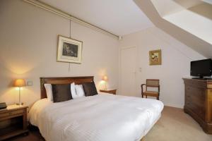 a bedroom with a large white bed and a tv at Hôtel Logis Le Relais De La Poste in Neuvéglise