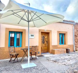 einen Tisch, zwei Stühle und einen Regenschirm vor einem Haus in der Unterkunft La Cabaña del Risco in Ligos