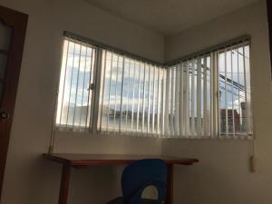 ein Fenster in einem Zimmer mit einem Tisch und einem blauen Stuhl in der Unterkunft Apartamento Dúplex - Barrio Maldonado Tunja in Tunja