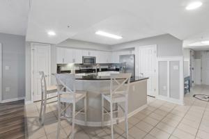 a kitchen with white cabinets and bar stools at Yacht Club Villas #2-504 condo in Myrtle Beach