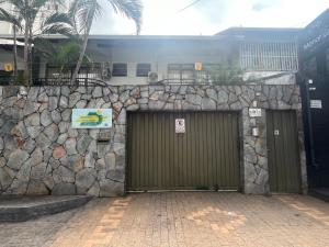 a building with two garage doors and a stone wall at Suíte completa no Bueno Somente para mulheres in Goiânia