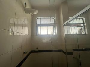 a bathroom with a shower and two windows in it at Suíte completa no Bueno Somente para mulheres in Goiânia