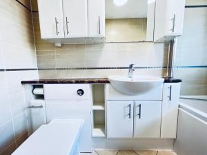 a bathroom with white cabinets and a sink at Rooms in stylish house in Milton Keynes