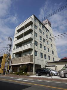 a tall white building with cars parked in front of it at Hotel Route-Inn Court Uenohara in Uenohara