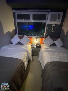 twee bedden in een kamer met een raam bij Nager Travellers Inn in Manilla