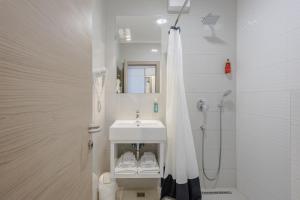 a white bathroom with a sink and a shower at Rogač Rooms & Restaurant in Omiš