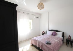 um quarto com uma cama com um cobertor rosa e uma janela em appartement confort calme propre em Marrakech