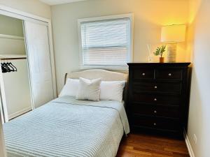 a bedroom with a bed with a dresser and a window at Charming and Convenient 3br 1ba apt - fully furnished and equipped - fast Internet in Forest Park