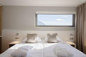 a bedroom with a bed with white sheets and a window at Rogač Rooms & Restaurant in Omiš
