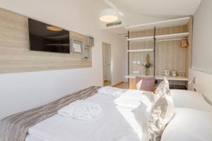 a bedroom with a white bed with a television on the wall at Rogač Rooms & Restaurant in Omiš