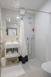 a white bathroom with a shower and a sink at Rogač Rooms & Restaurant in Omiš