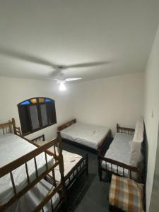 a room with three bunk beds and a flat screen tv at Casa na praia, 15 min de caminhada in Itanhaém