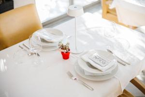a white table with plates and glasses on it at Rogač Rooms & Restaurant in Omiš