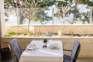 a table with a white tablecloth and chairs in front of a window at Rogač Rooms & Restaurant in Omiš