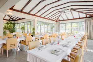 una sala da pranzo con tavoli e sedie bianchi e finestre di Rogač Rooms & Restaurant a Omiš (Almissa)