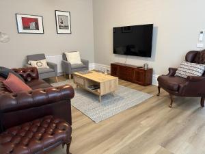 sala de estar con muebles de cuero y TV de pantalla plana en Rodonia - Cottage in Kew en Melbourne