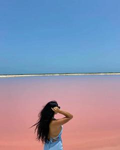 a woman with long black hair standing in front of a pink at HOTEL LAS COLORADAS in Yuluc