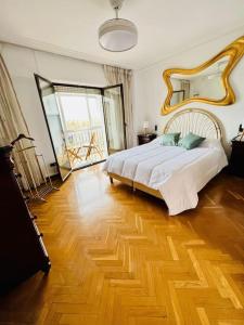 a bedroom with a large bed and a wooden floor at A Orillas del Pilar con parking in Zaragoza