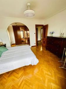 a bedroom with a white bed and a wooden floor at A Orillas del Pilar con parking in Zaragoza