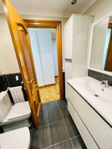 a bathroom with a sink and a toilet and a mirror at A Orillas del Pilar con parking in Zaragoza