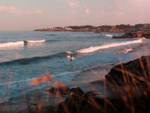 una persona parada en el océano con una tabla de surf en Gîte Saint-Brevin-les-Pins, 2 pièces, 2 personnes - FR-1-306-1242, en Saint-Brevin-les-Pins