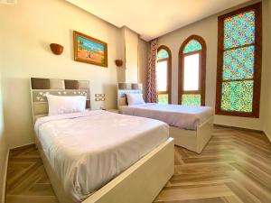 two beds in a room with stained glass windows at New Abusimble 2 Hotel & Restaurant in Abu Simbel