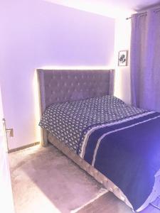 a purple bed in a room with a curtain at Très jolie F2 cosy 45m2 avec balcon et parking proche Paris in Livry-Gargan