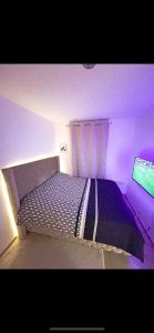 uma cama num quarto com luz roxa em Très jolie F2 cosy 45m2 avec balcon et parking proche Paris em Livry-Gargan