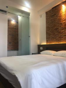 ein Schlafzimmer mit einem großen weißen Bett und einer Ziegelwand in der Unterkunft miniHomestay green view - single room - AC and bathtub - Ea Kar - Dak Lak in Buôn Mhang