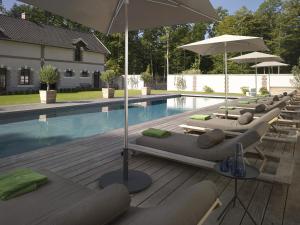 a row of lounge chairs and umbrellas next to a swimming pool at Chateau De La Resle - Design Hotels in Montigny-la-Resle