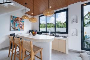 a kitchen with a island with chairs and windows at Villa Greenland Canggu by Nagisa Bali in Dalung
