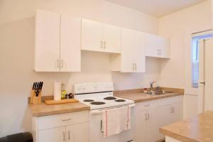 a white kitchen with a stove and a sink at NEW Downtown MJ Parking Near Tunnels, Casino & Spa Coffee in Moose Jaw
