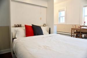 a bedroom with a large white bed with red pillows at Cozy Studio Perfect for Business Travelers Downtown in Moose Jaw