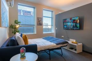 溫尼伯的住宿－New Listing Luxurious Downtown Loft Heated Parking Rooftop Patio BBQ Gym Coffee，一间卧室配有一张床、一张沙发和一台电视。