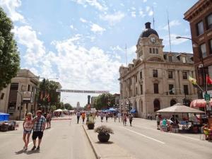 a group of people walking down a city street with a clock tower at Cozy Studio Perfect for Business Travelers Downtown in Moose Jaw