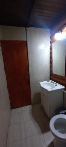 ein Badezimmer mit einem Waschbecken, einem WC und einem Spiegel in der Unterkunft Cabaña de Troncos en Colonia Suiza in Mendoza
