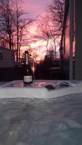 a bottle of wine and a glass on a table with the sunset at 16 Leaf Lane Country Retreat in Newton on the Moor