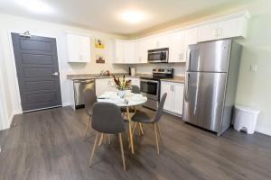 a kitchen with a table and a stainless steel refrigerator at Brand new Gorgeous Condo Near UNB & Hospital Coffee Parking 202 in Saint John