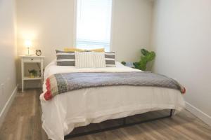 a bedroom with a bed with pillows and a window at Gorgeous Modern 2BD Condo Heart of Wpg Coffee Location in Winnipeg