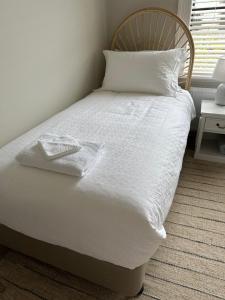 Rodonia - Cottage in Kew في ملبورن: سرير عليه أغطية ووسائد بيضاء