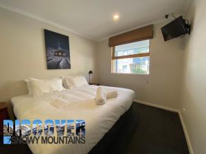 a bedroom with a large white bed with a window at Tomarlin Views 1 in Thredbo
