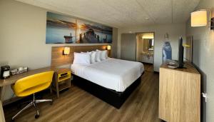 a hotel room with a bed and a desk and a television at Days Inn by Wyndham Cloverdale Greencastle in Cloverdale